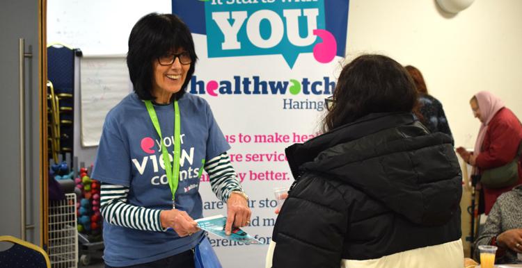 Healthwatch volunteer on a stand talking to a woman