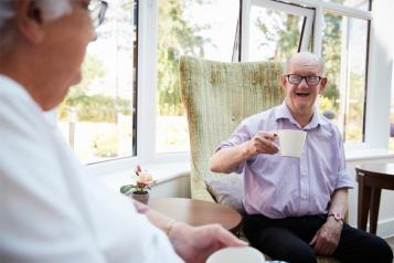 Man talking to an elderly man sitting down