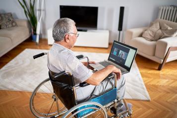 White older man in a wheelchair chatting online