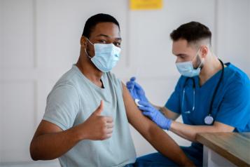 Black male thumbs up having a vaccine