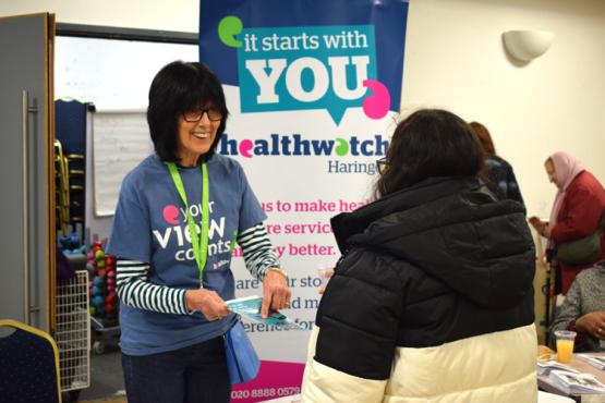 Healthwatch volunteer on a stand talking to a woman