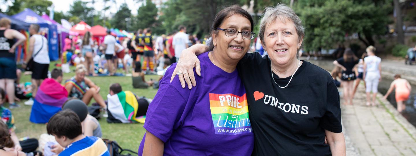 Two women at a pride march with their arms round each other