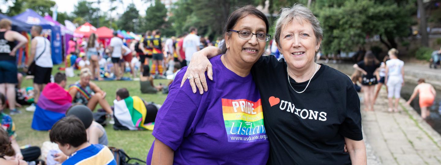 Two women at a pride march with their arms round each other