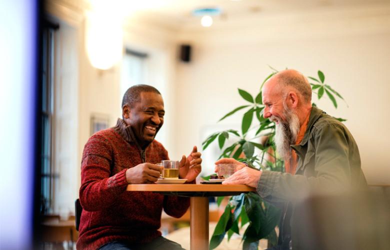 Two men sitting by a table laughing together